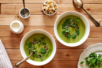 broccoli puree soup with sesame seeds, croutons and herbs. wooden background, top view