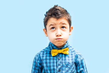 portrait of a dreaming boy. Boy in shirt and bow tie on blue background