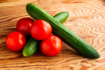 two cucumbers and four tomatoes on a wooden background