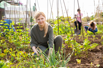 Portrait of female amateur gardener working with family in kitchen garden in springtime