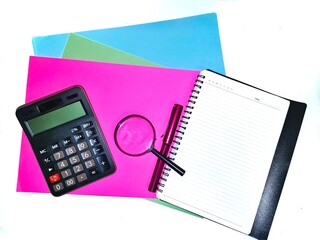 A note book with a magnifying glass, calculator, A4 paper and a pen isolated on white background.