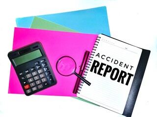 Accident report wording. Written on a note book with a magnifying glass, calculator and a pen on colorful A4 paper background.