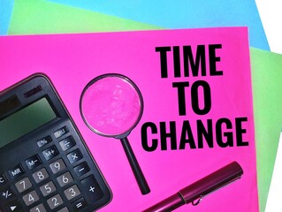Time to change. Written on a pink paper with a magnifying glass, calculator and a pen.