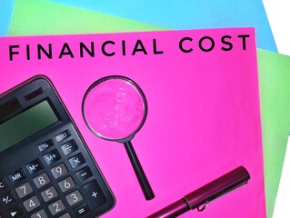 Financial Cost. Written on a pink paper with a magnifying glass, calculator and a pen.