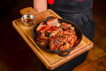 Assorted delicious grilled meat served in a frying pan on a wooden board.