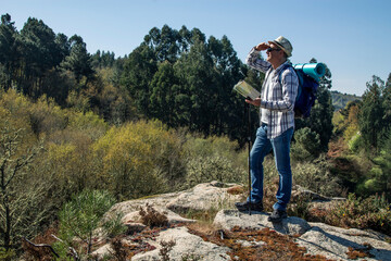 mountaineer on top of the hill with map scanning the horizon