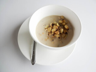 Sweet lotus seed sweetened with coconut milk in white bowl and white saucer with spoon. From view above
