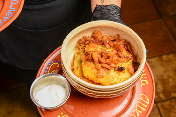 Delicious potato pancakes with roasted onions served in a ceramic bowl by waiter.