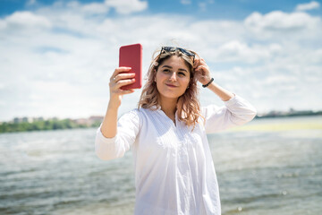 Charming young woman  in a white dress enjoy nature by the lake at sunny day