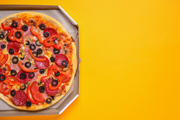 A whole, cooked and sliced peperoni pizza on a colorful yellow backgroud, various colors.
