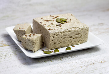 Halva close-up on a white plate on a white wooden background. Traditional oriental dessert sweet halva. Halva made from sunflower seeds. side view, copyspace.