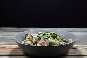 Traditional spicy squid (octopus) salad mixed with sliced shallot and chilly serving on the plate. Famous seafood menu in Asian restaurant. 