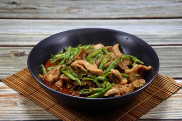 Traditional fried string bean and chopped chicken thigh mixed red curry paste serving on the plate. Famous hot and spicy food in Asia restaurant. 