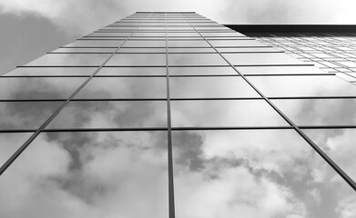 View of a modern glass skyscraper. A reflection of the cloudy sky in a glass skyscraper. Black and white photo