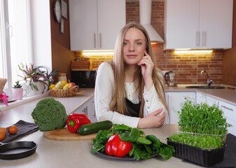 A young happy lady standing in the kitchen while cooking.