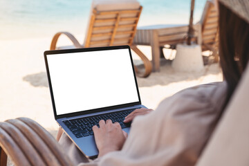 Mockup image of a woman using and typing on laptop computer with blank desktop screen while sitting...