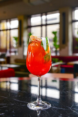 Refreshing fruit punch beverage with lemon in glass on black table with blurred backgrond. In restaurant or cafe.