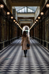 A woman in a coat walking in a passage in Paris