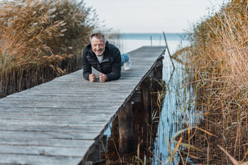 Happy healthy man working out n a wooden jetty or boardwalk