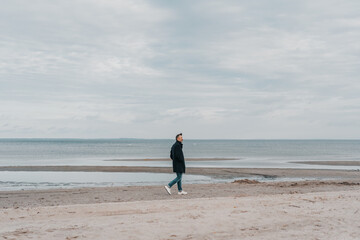 Lonely man walking along a deserted sandy beach in winter