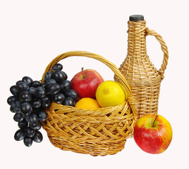 Basket with apples and grapes on the background of a bottle with wine.Isolated on white.