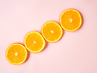 Diagonal line of orange circles on pink background. Orange slices border with copy space. Free space for text or product. Flat lay, top view.