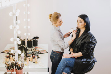 Makeup master doing makeup to beautiful model indoor beauty studio