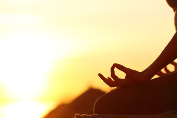 Woman hand silhouette doing yoga at sunset
