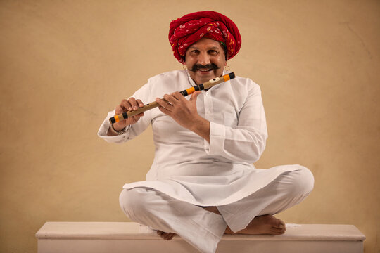 A HAPPY TURBANED MAN SITTING WITH HIS FLUTE TO PLAY	