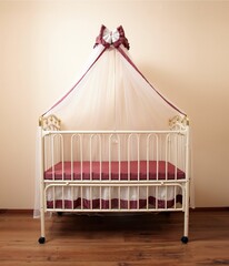 White metal four-poster bed for a newborn baby in the interior of the room. Baby cot.