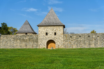 Fototapeta premium Old medieval castle wall with tower and big grass field