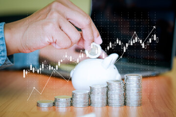 Business men put the coins into the white piggy bank and the coins stacks were lined up in front. The idea of ​​saving money to be used in the future. Financial and business concept
