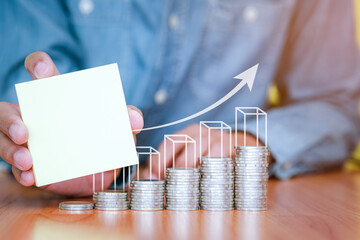 A businessman holding a blank note with coins stack placed on the front. Saving and investment concept for the future. copy space for text.