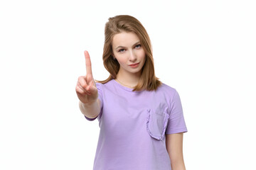 Fototapeta premium Serious young woman look at camera make warning sign. Girl raises finger up, says: Attention please