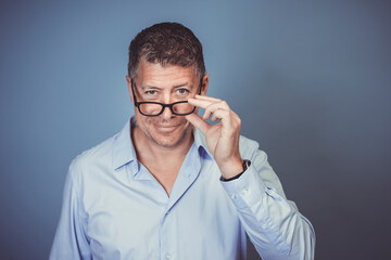 Fototapeta na wymiar businessman with black glasses and blue shirt posing against blue background in the studio