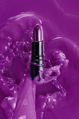 Purple lipstick in violet liquid flow. Top view.