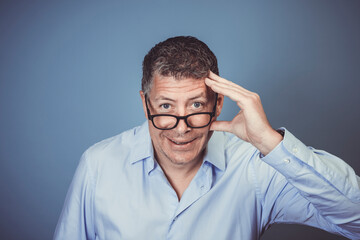 businessman with black glasses and blue shirt posing against blue background in the studio