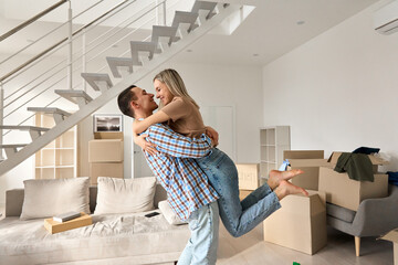 Happy independent couple first time home owners hugging in living room on moving day. Young man and...