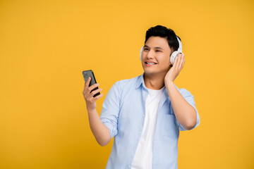 Handsome young Asians using a smartphone and wireless headphones. He listens to music on the phone.