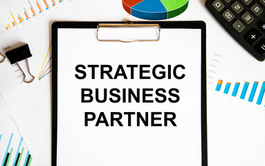 Strategic BUSINESS PARTNER text, paper clip, calculator, diagrams and graphs next to the letter tablet.