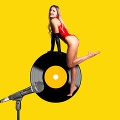 Sexy, young woman with red bodysuit. Manipulation with a vinyl record on a yellow background