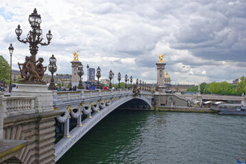 Fototapeta na wymiar View of the Pont Alexandre lll. On the bridge are pedestrians and cars