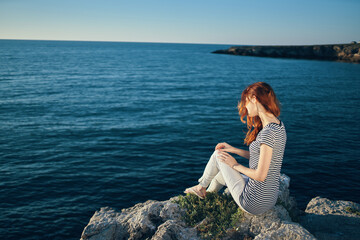 romantic woman on a rock near the sea in the mountains sunset summer back view