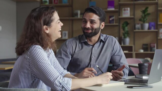 Two happy diverse business people professional employees workers having fun discussion working together laughing at office meeting. Indian teacher and latin student having friendly conversation.