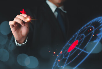 Businessman hand holding red dart put to centre of red target board. Concept Setting life goals,...