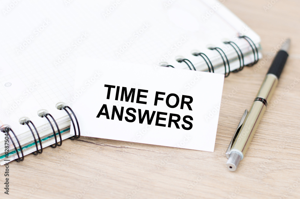 Aufkleber on the table next to a notebook and a gold pen a card with the text time for answers.