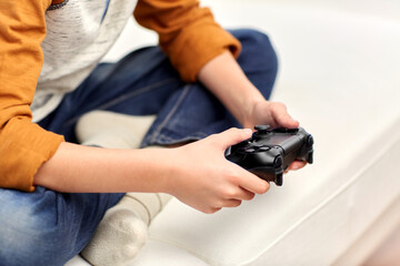 leisure, technology and people concept - boy with gamepad playing video game at home