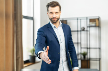 Confident businessman in blur, focus on the hand of businessman, dressed in suit, handshake for concluding the deal, ending of successful negotiate, hand shake with partner to celebration partnership