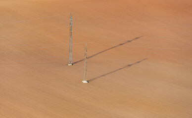 Electricity transmission towers in the middle of the empty field.