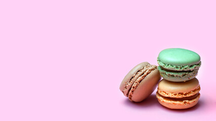 Macaroons in tender color on a pink background banner. Wallpaper with delicious juicy french desserts.